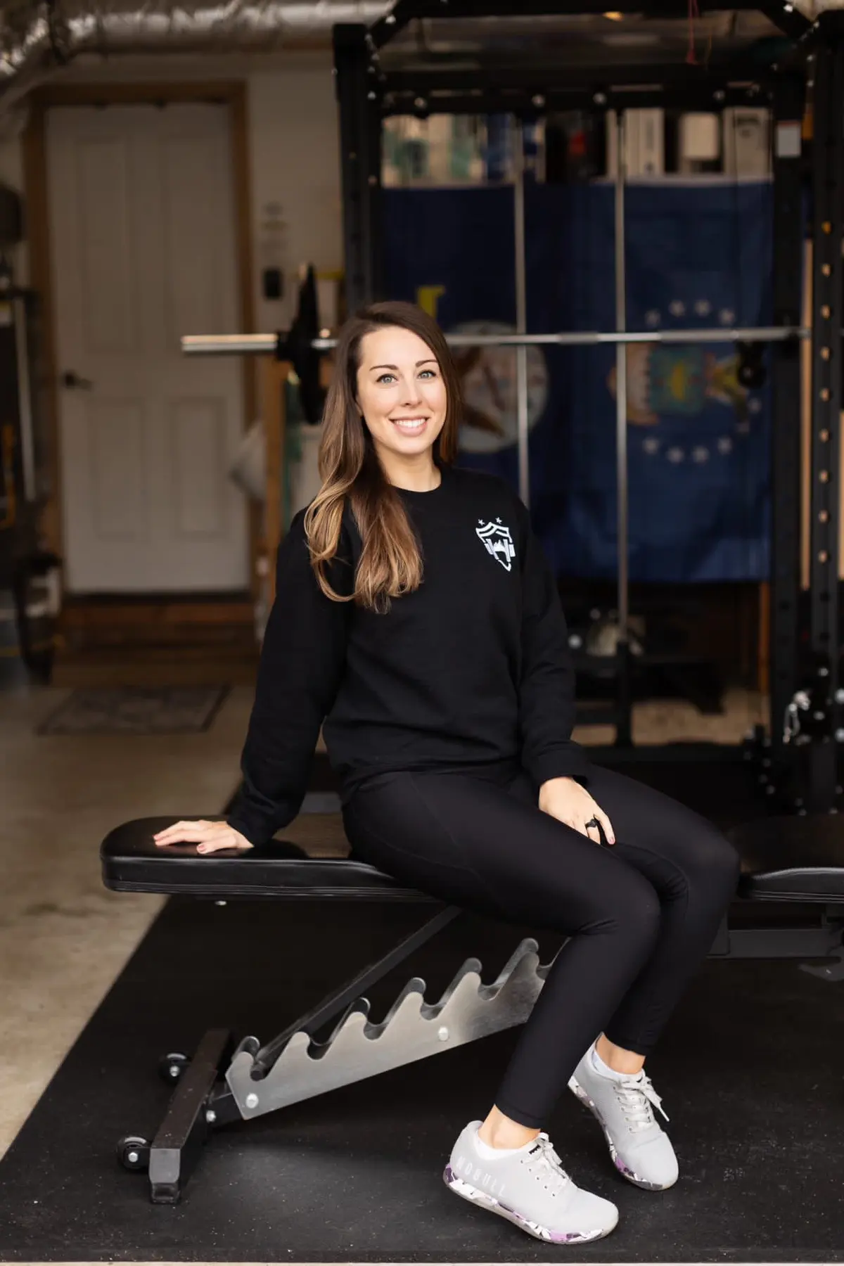 Female personal trainer sitting on a bench in her garage gym
